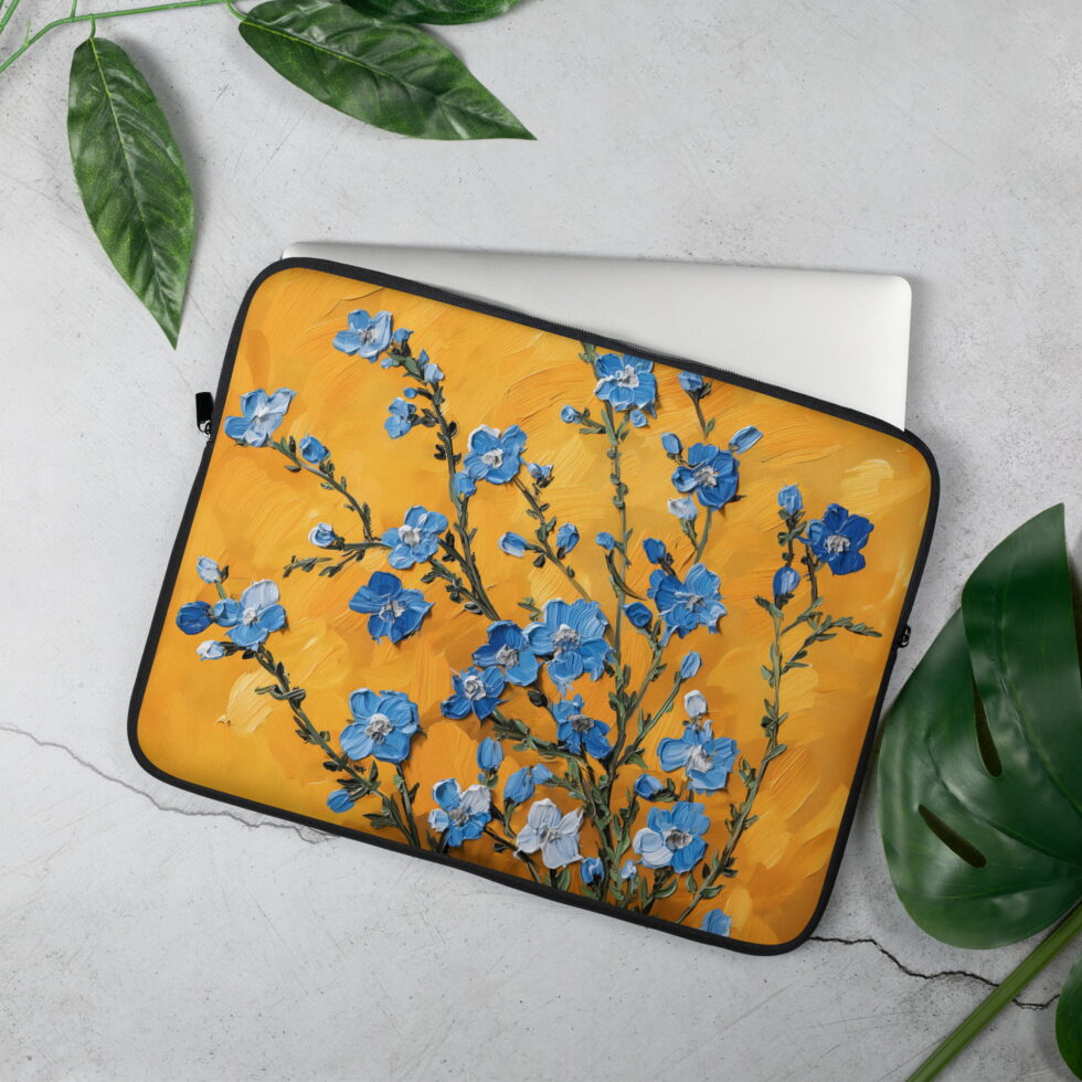 Laptopu aizsargājošs maks 15", attēlots mokaps uz galda virsmas, māksliniecisks dizains ar ziliem ziediem uz oranža fona