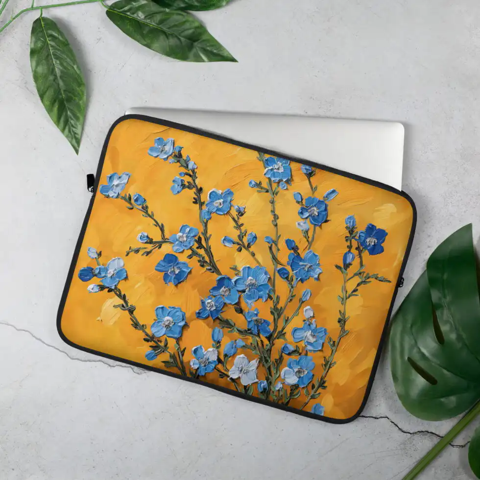 Laptopu aizsargājošs maks 15", attēlots mokaps uz galda virsmas, māksliniecisks dizains ar ziliem ziediem uz oranža fona