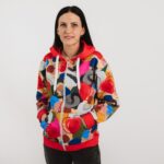 jaka ar kapuci, dizainā izmantotas abstraktas formas krāsaini elementi, redzama uz sievietes auguma