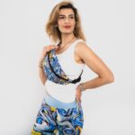 krāsaina dizaina jostas somiņa ar košiem abstraktiem akcentiem, uz modeles parādīta aplikta kā maza pleca somiņa